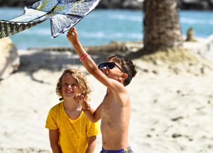 Kinder spielen mit einem Drachen am sonnigen Strand.