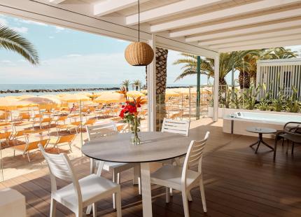 Elegante Terrasse mit Meerblick, gelben Sonnenschirmen und Whirlpool.