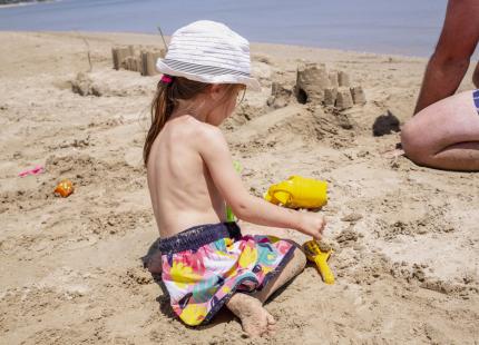 Kind spielt am Strand und baut Sandburgen.