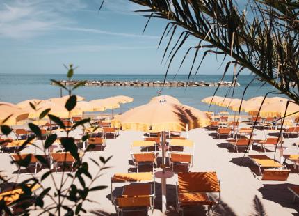 Strand mit orangefarbenen Sonnenschirmen und ruhigem Meer.