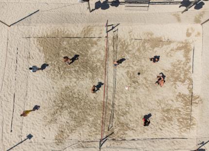 Luftaufnahme eines Beachvolleyballspiels auf Sand.