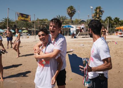 Junge Leute feiern mit Medaillen am Strand während eines Rennens.