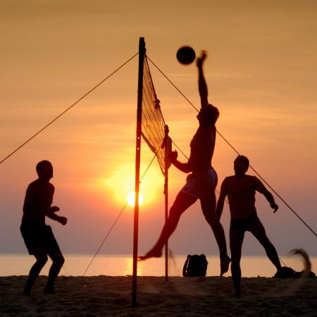 Beach volleyball players at sunset on the beach.