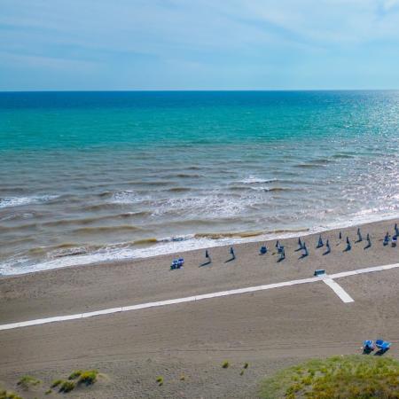 Quiet beach with closed umbrellas and calm sea.