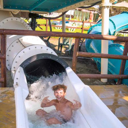 Happy boy slides down water slide at the water park.