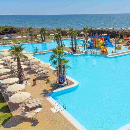 Pool with slides by the sea, umbrellas and palm trees.