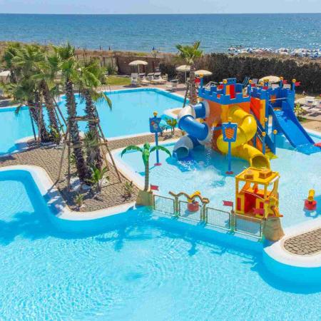 Pool with colorful slides by the sea, perfect for kids.