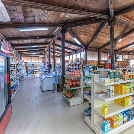 A store with shelves of food and drinks, natural lighting, and wood.