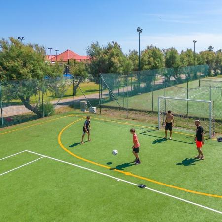 Four people playing soccer on an outdoor field.