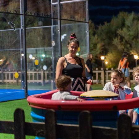Children play outside at night, watched by adults.