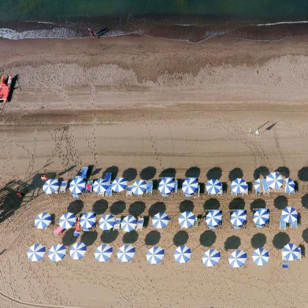 Aerial view of a beach with blue and white umbrellas.