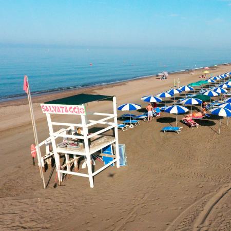 Beach with blue and white umbrellas and a lifeguard tower.