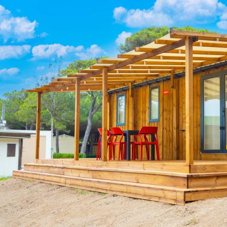 Wooden house with a porch and red chairs outside.