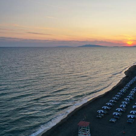 Beach at sunset with aligned umbrellas and calm sea.