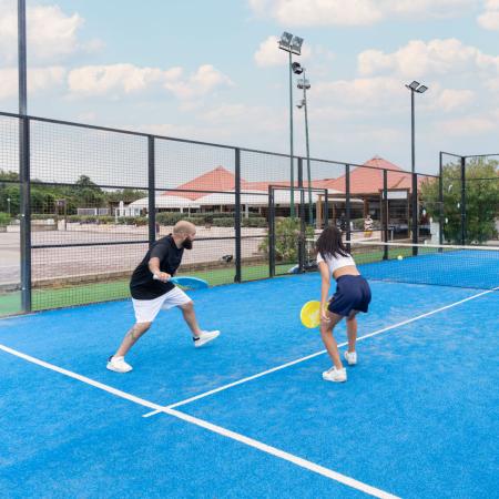 Padel players on a blue outdoor court.