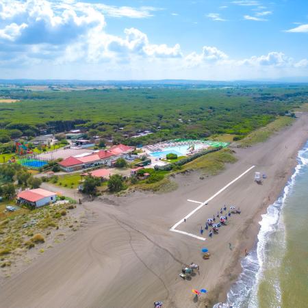 Scenic beach with a beach resort and pool surrounded by greenery.