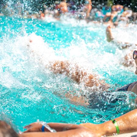 People having fun in the pool, water splashing everywhere.