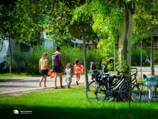 Family camping with bicycles and camper, heading towards a destination.