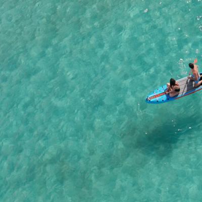 Due persone su una tavola da paddle in acque cristalline.