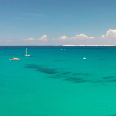 Mare turchese con barche e cielo sereno.