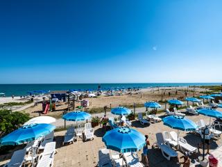 Beach with blue umbrellas and loungers under a clear sky.
