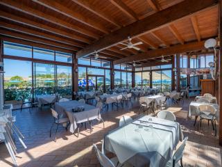 Bright restaurant with large windows, set tables, and outdoor view.
