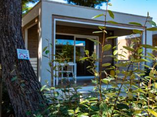 Modern house with garden signage, surrounded by trees.