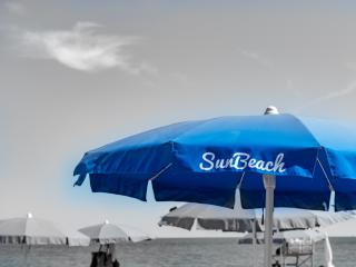 Blue beach umbrella with sea and clear sky.