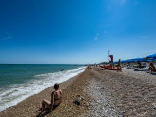Sunny beach with blue umbrellas and calm sea.