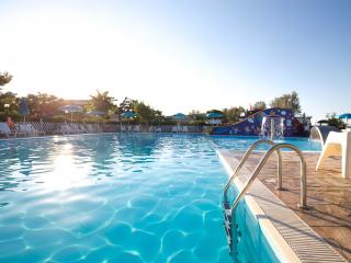 Outdoor pool with slide and sun loungers.