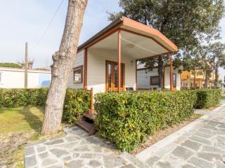 Wooden cabin with porch, surrounded by hedges and trees.