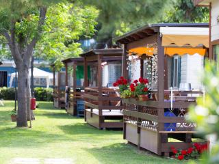 Bungalows with flowers and porches in a green campsite.