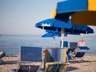Beach with blue umbrellas and deck chairs.