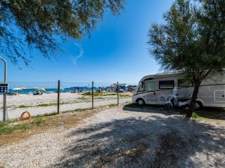 Camper parked near the beach with colorful umbrellas.