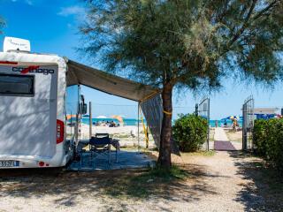 Camper near the beach, colorful umbrellas and blue sea.