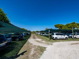 Outdoor parking with canopies, parked cars, and clear sky.