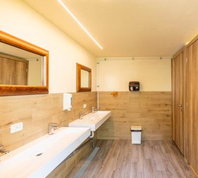 Bagno moderno con lavandini doppi, specchi e porte in legno.