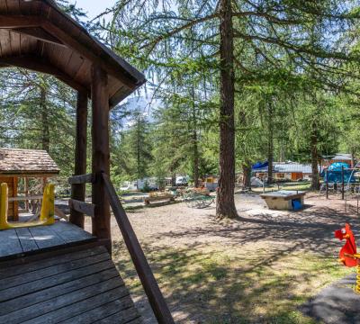 Parco giochi all'aperto in un campeggio boschivo con strutture per bambini.