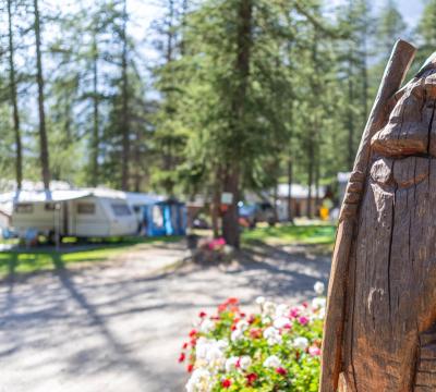 Scultura in legno in un campeggio tra alberi e roulotte.