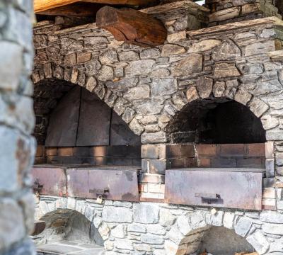 Forno in pietra rustico con archi e sportelli metallici.