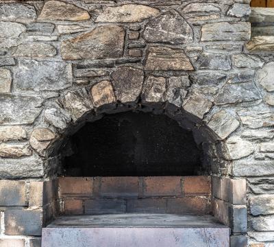 Forno a legna in pietra con sportello metallico.