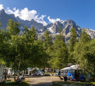 Campeggio tra gli alberi con vista sulle montagne innevate.