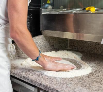 Uomo prepara impasto su un piano di lavoro in cucina.