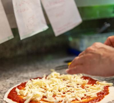 Preparazione di una pizza con salsa di pomodoro e formaggio.