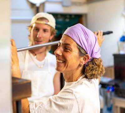 Due persone cucinano insieme in una cucina, sorridendo.