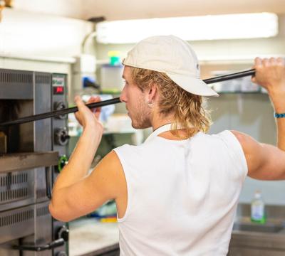 Persona che inforna una pizza in un forno professionale.