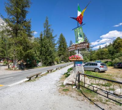 Ingresso del Camping-Pizzeria Grandes Jorasses tra alberi e montagne.