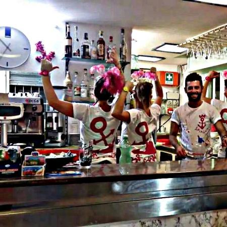 Cheerful bartenders with white shirts and pink decorations behind the counter.