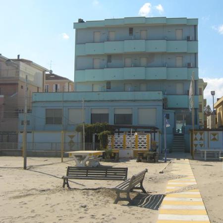 Blue beachfront building with bench and sand.