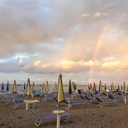 Beach with sunbeds and a double rainbow in the sky.